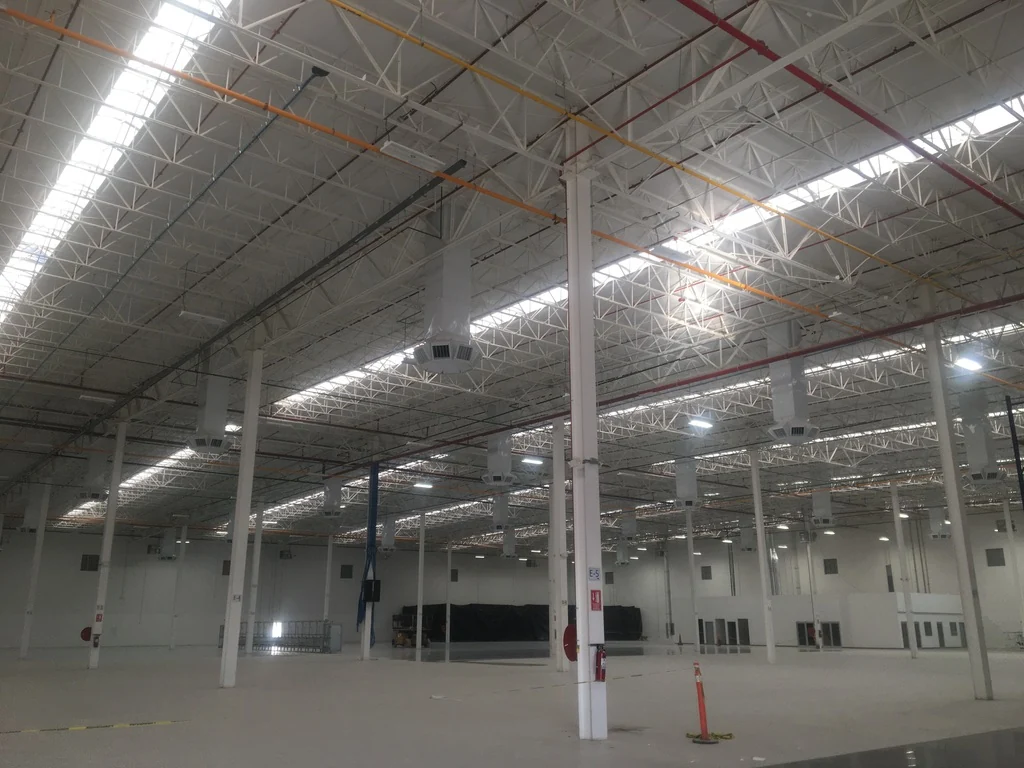Distribución de aire mediante ductos y difusores en el interior de una planta industrial